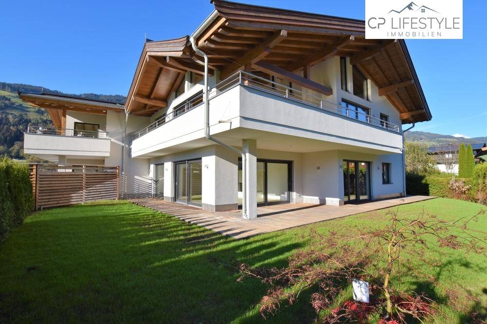 Modernes Wohnhaus mit mehreren Balkonen, großen Fenstern und gepflegtem Gartenbereich.