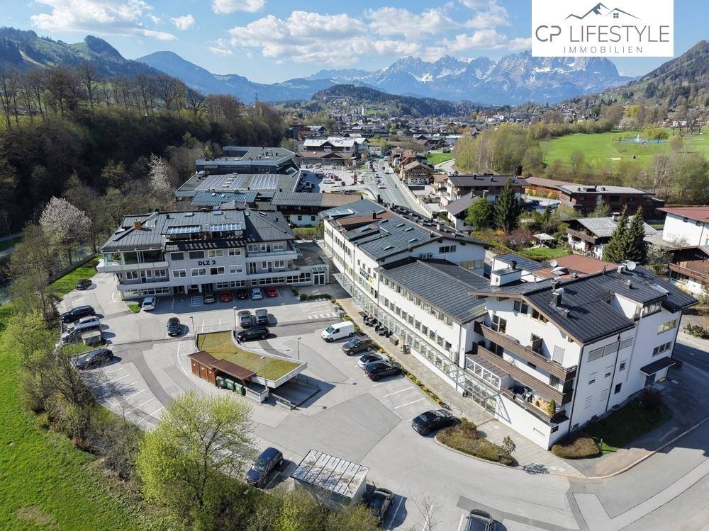 Weitläufige Luftaufnahme eines Geschäftskomplexes in einer malerischen Bergregion mit Parkmöglichkeiten.