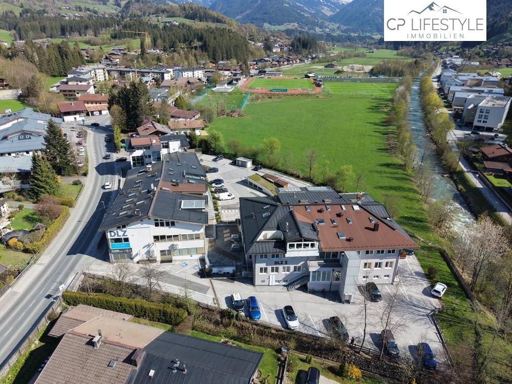 Luftbild eines Gewerbegebiets mit mehreren Gebäuden, umgeben von weitläufigen Grünflächen und einer Straße.