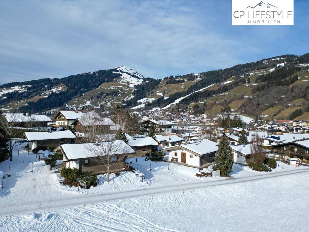 Weitläufige Ansicht einer Chalet-Siedlung in einer verschneiten Bergregion mit einem Dorf im Tal.