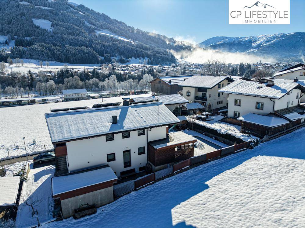 Panoramablick auf das Anwesen und die verschneite Umgebung mit sonnigen Berghängen im Hintergrund.