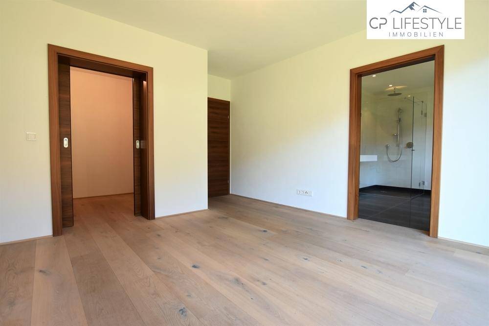 Heller Flurbereich mit Holzboden und Zugang zu verschiedenen Zimmern, inklusive Badezimmer.