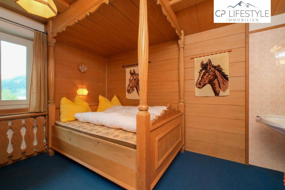 Rustikales Schlafzimmer mit Himmelbett aus Holz, Holzvertäfelung und blauer Teppichboden.