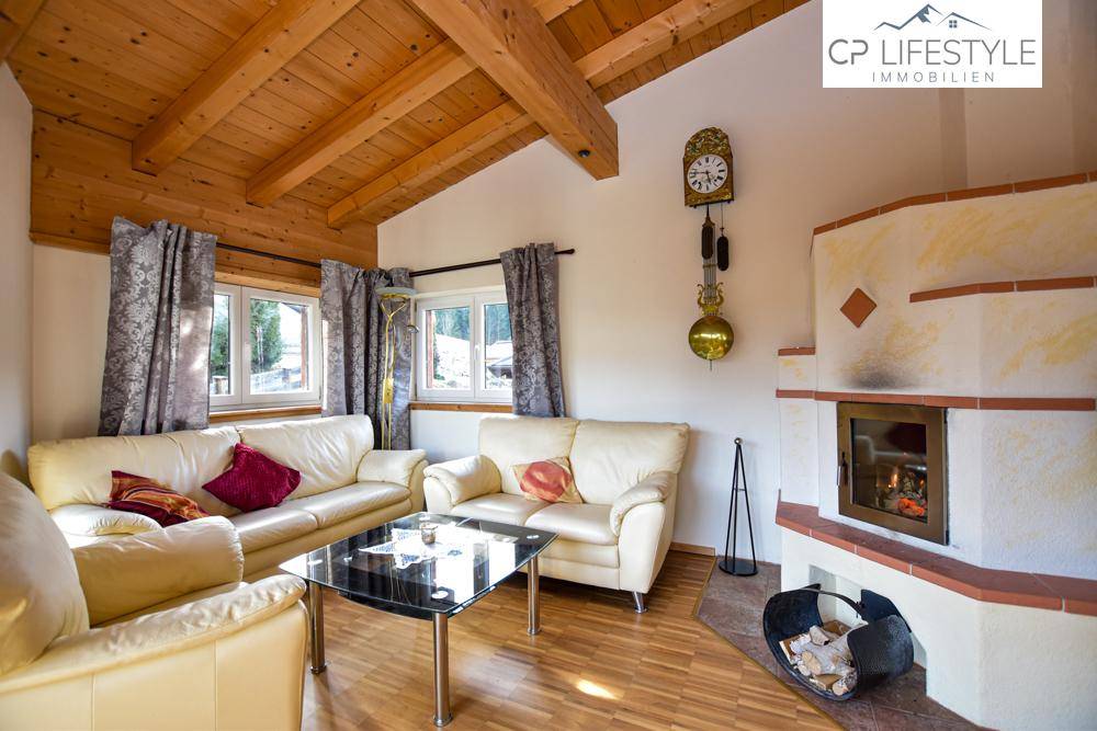 Gemütliches Wohnzimmer mit Kamin, Ledersofas und hoher Holzbalkendecke.