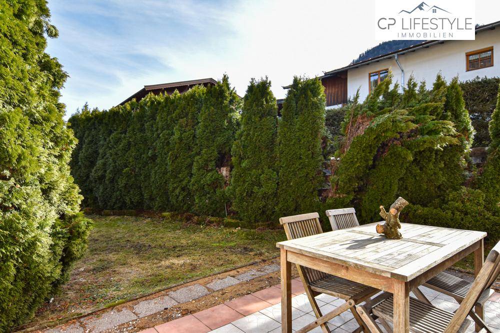 Gepflegter Garten mit Sitzbereich und hoher Hecke, ideal für entspannte Stunden im Freien.