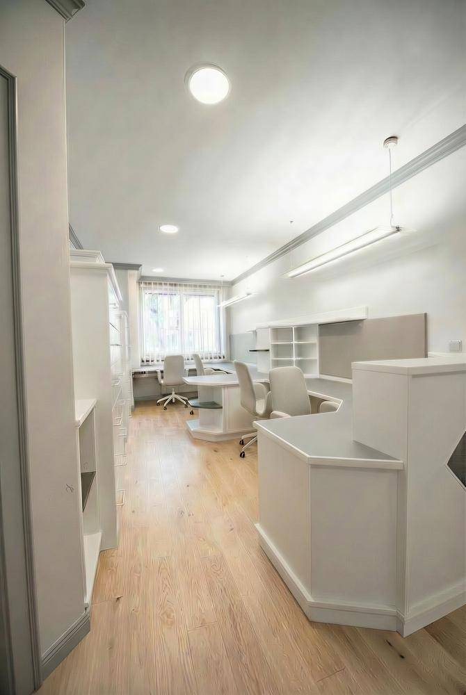 Offener Bürobereich mit mehreren Arbeitsplätzen, hellem Holzboden und viel Tageslicht durch große Fenster.