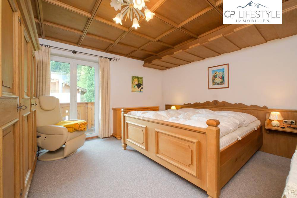 Gemütliches Schlafzimmer mit Holzbett, Holzdecke und Zugang zum Balkon.