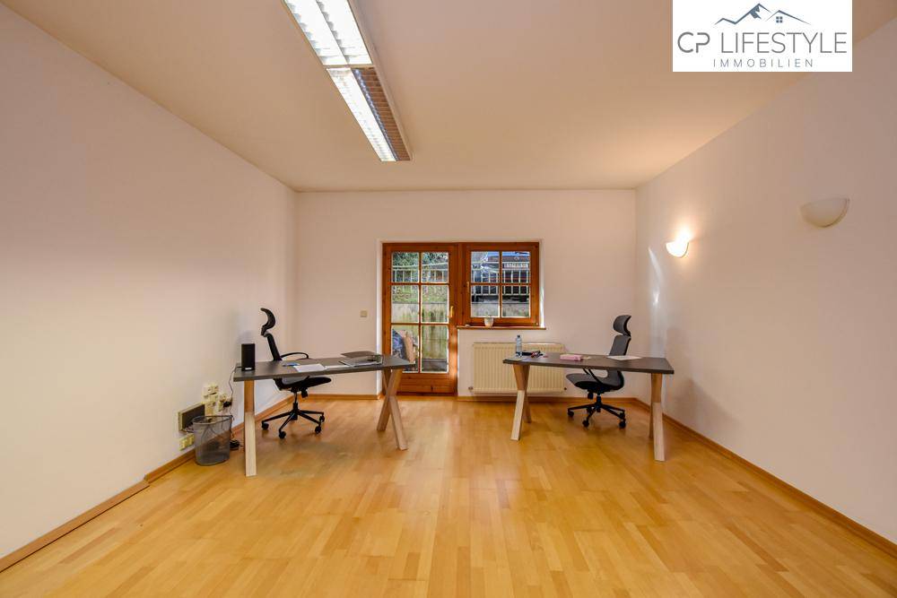 Helles Büro mit Holzboden, zwei Arbeitsplätzen und Blick nach draußen durch die großen Fenstertüren.