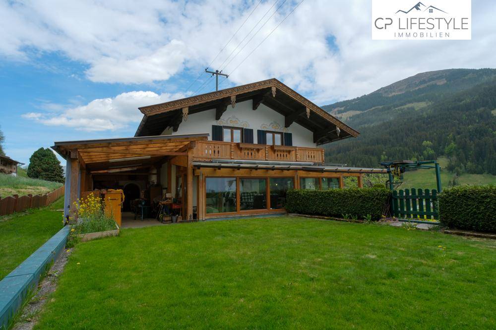 Traditionelles Haus mit großem Rasen und verglastem Anbau in ländlicher Umgebung.