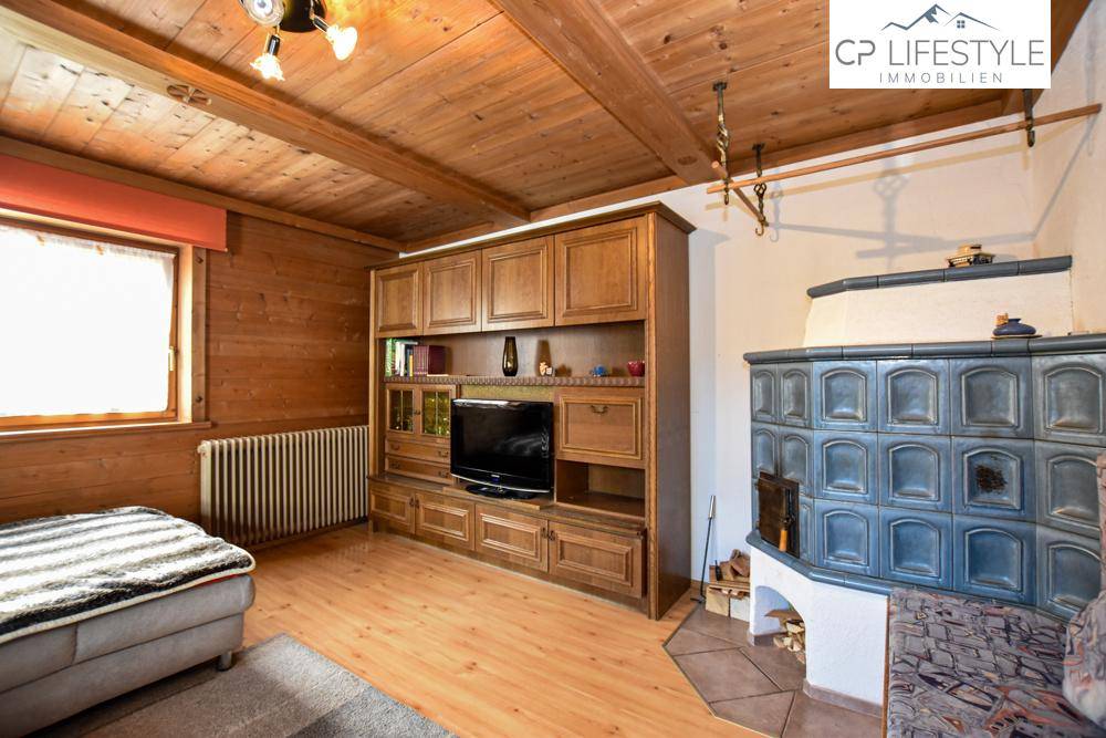 Gemütliches Wohnzimmer mit traditionellem Kachelofen, Holzböden und rustikaler Einrichtung.