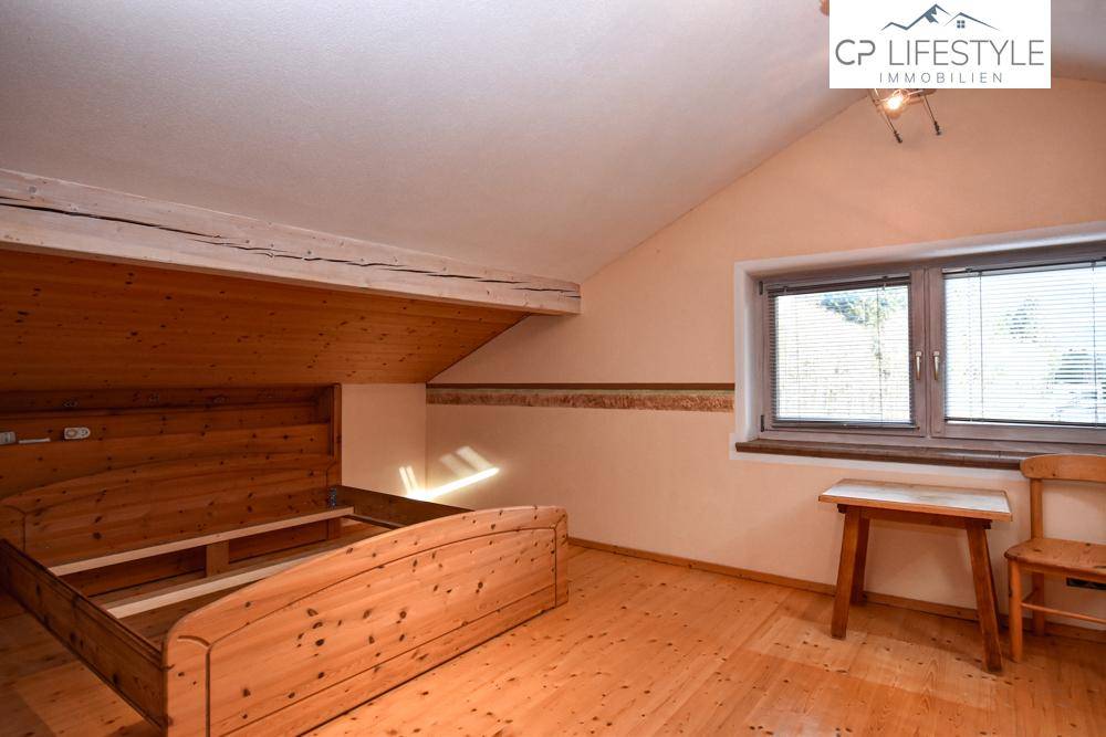 Geräumiges Schlafzimmer im Dachgeschoss mit Holzboden und schrägen Wänden.