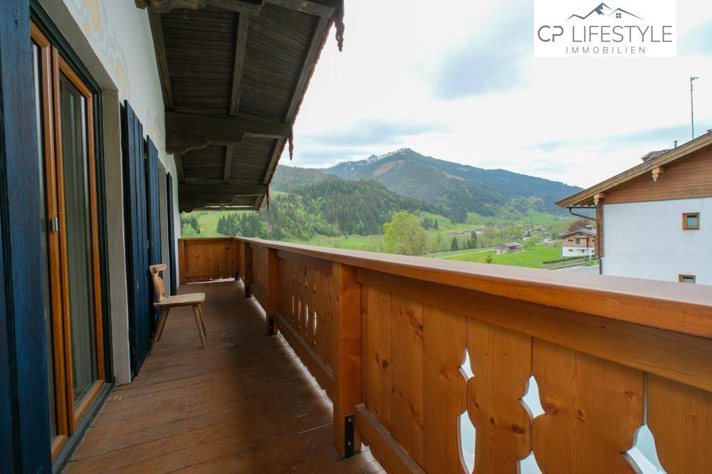 Langer Holzbalkon mit Bergblick und traditionellem Geländer.