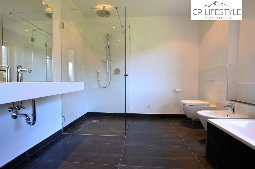 Modernes Badezimmer mit ebenerdiger Glasdusche, Doppelwaschbecken und Bidet.