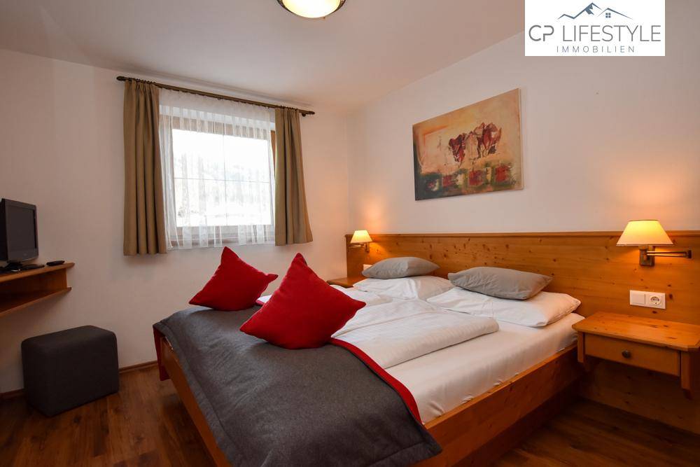 Gemütliches Schlafzimmer mit Doppelbett, Holzmöbeln und einem Fenster mit Blick auf die winterliche Umgebung.