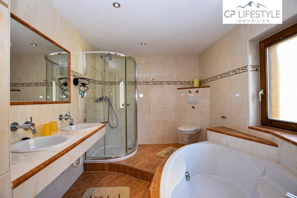 Funktionales Badezimmer mit Eckbadewanne, Duschkabine, Doppelwaschbecken und Fenster.