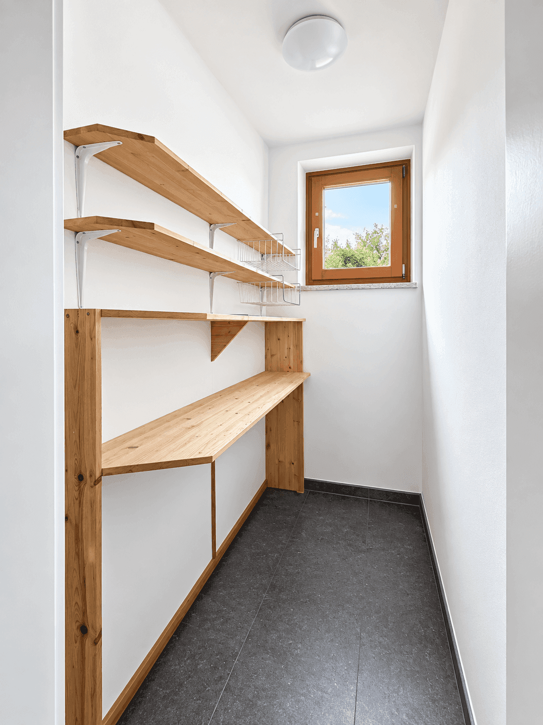 Praktischer Abstellraum mit Holzregalen, Fenster und Fliesenboden.