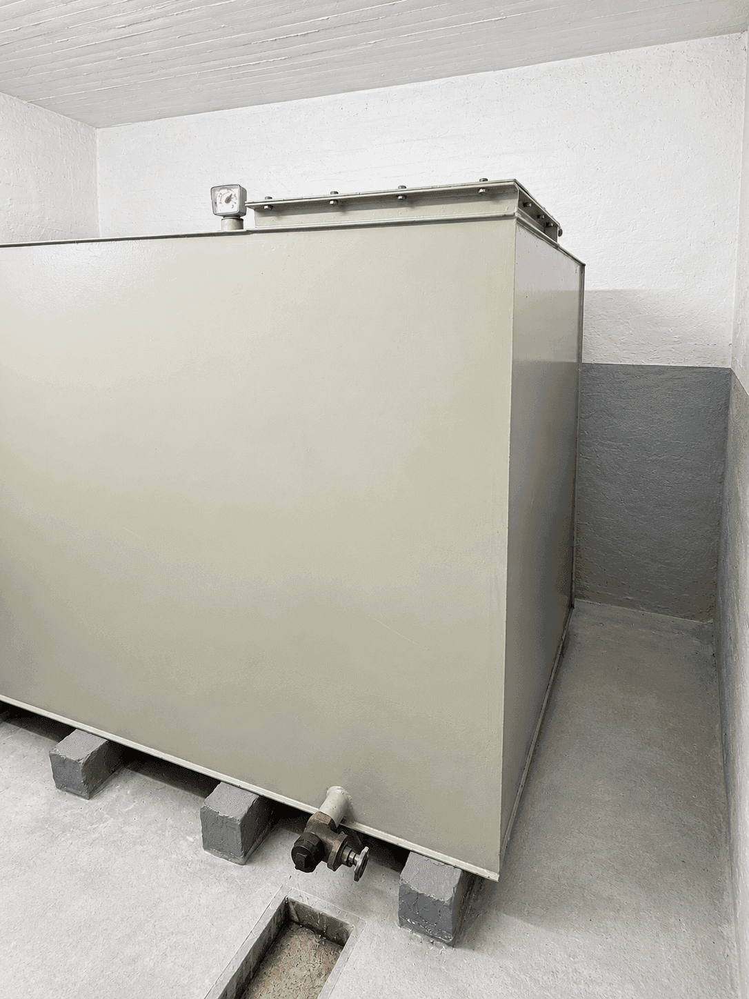 Lagerraum mit großem, rechteckigem Tank auf Betonblöcken.