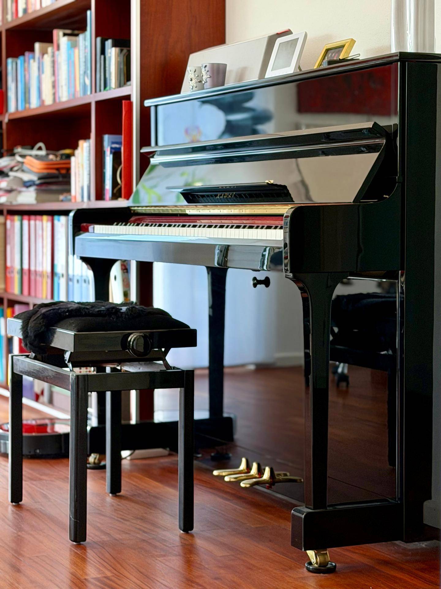 Klassisches Klavier in einem Wohnbereich mit Bücherregal und elegantem Holzboden.