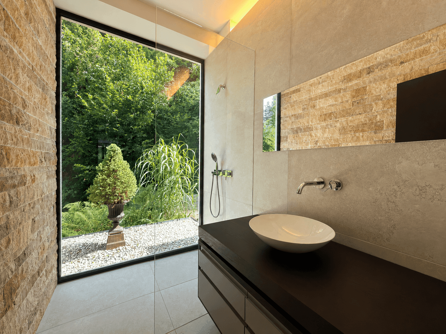 Modernes Badezimmer mit großer Fensterfront, begehbarer Dusche und Natursteinwand.