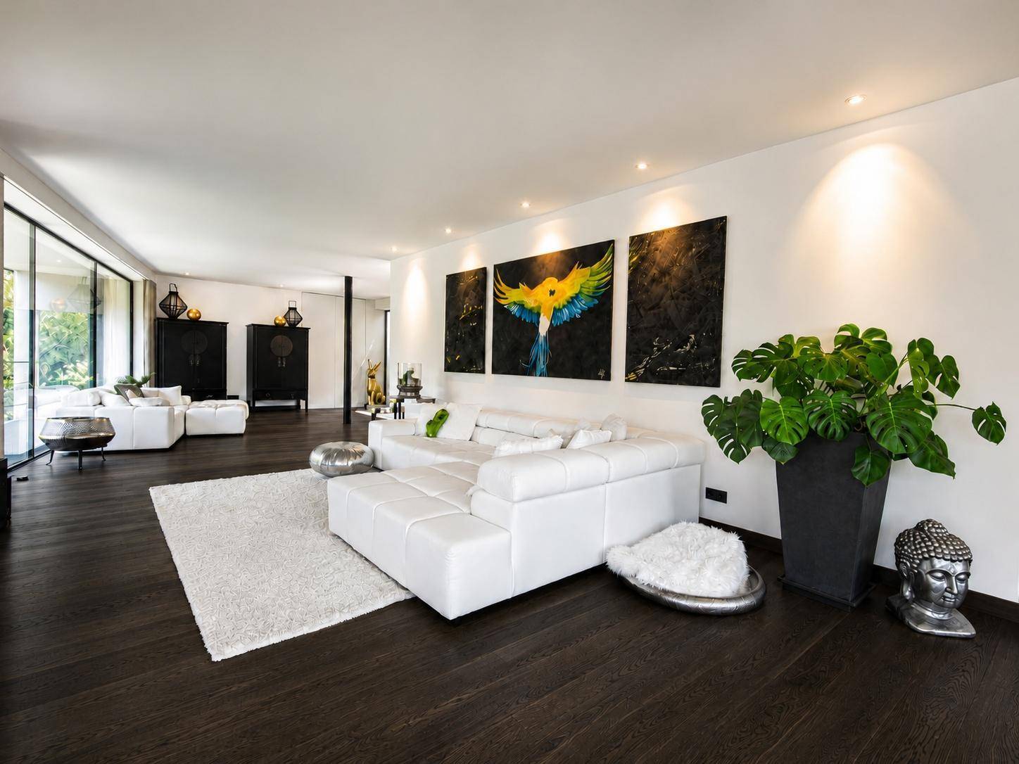 Geräumiges Wohnzimmer mit weißer Eckcouch, dunklem Holzboden und moderner Kunst an der Wand.