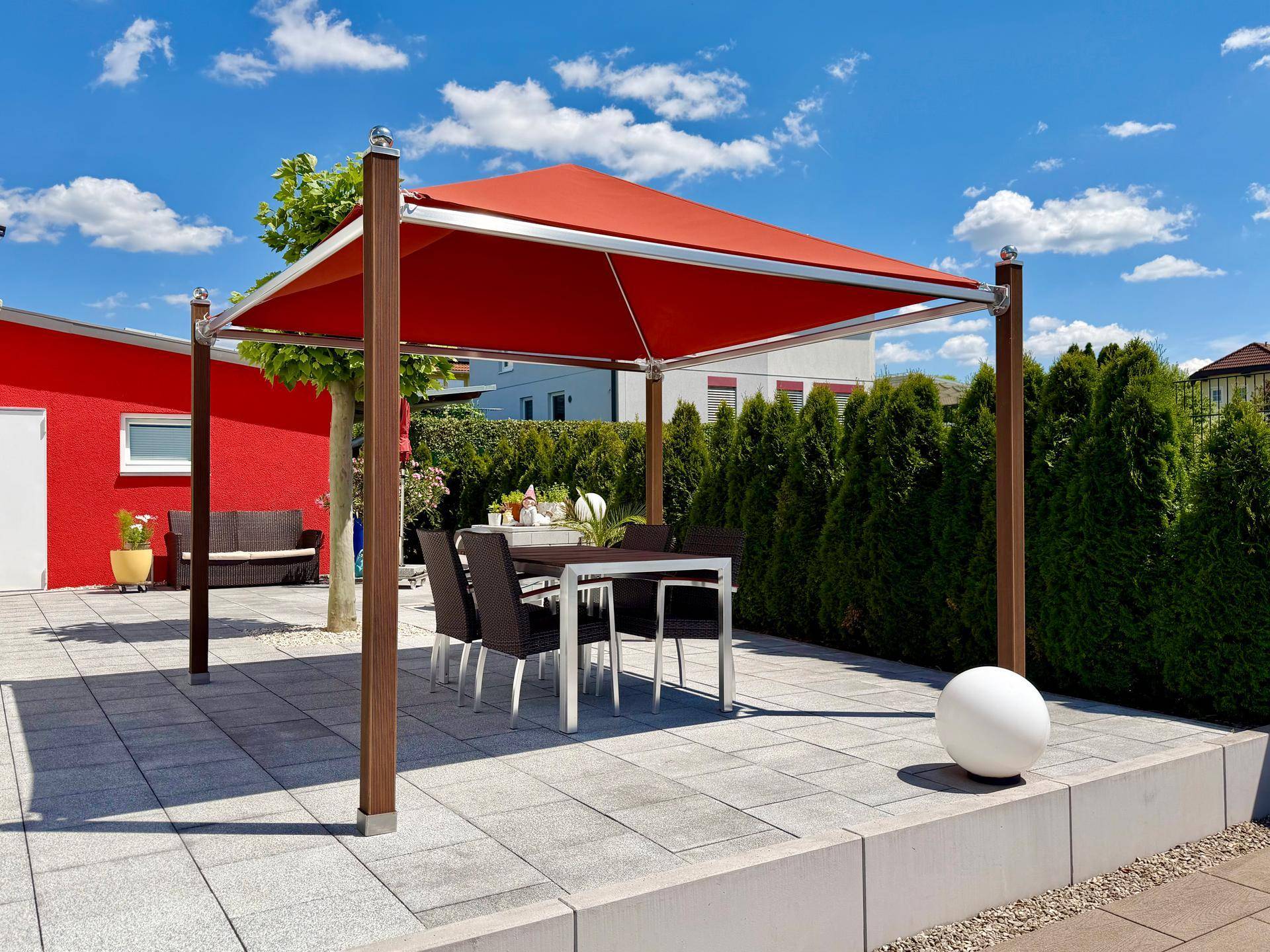 Gemütliche Terrasse mit rotem Sonnensegel und Esstisch im Freien für entspannte Stunden.