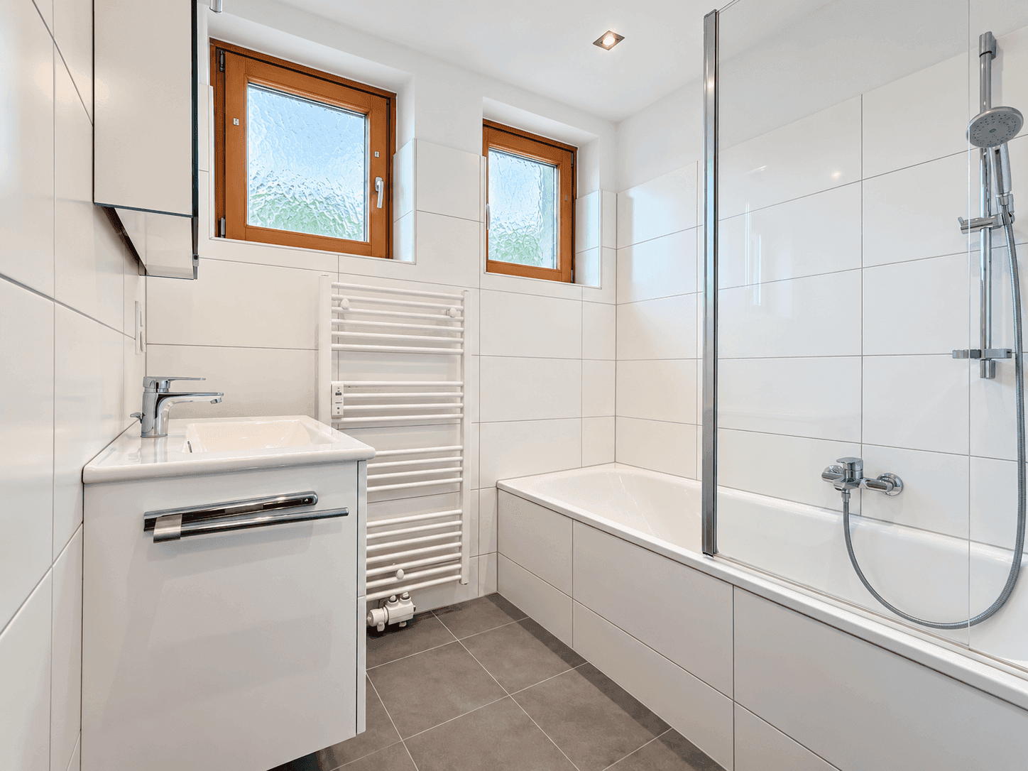 Modernes Badezimmer mit Badewanne, Dusche, Waschbecken und beheiztem Handtuchhalter.