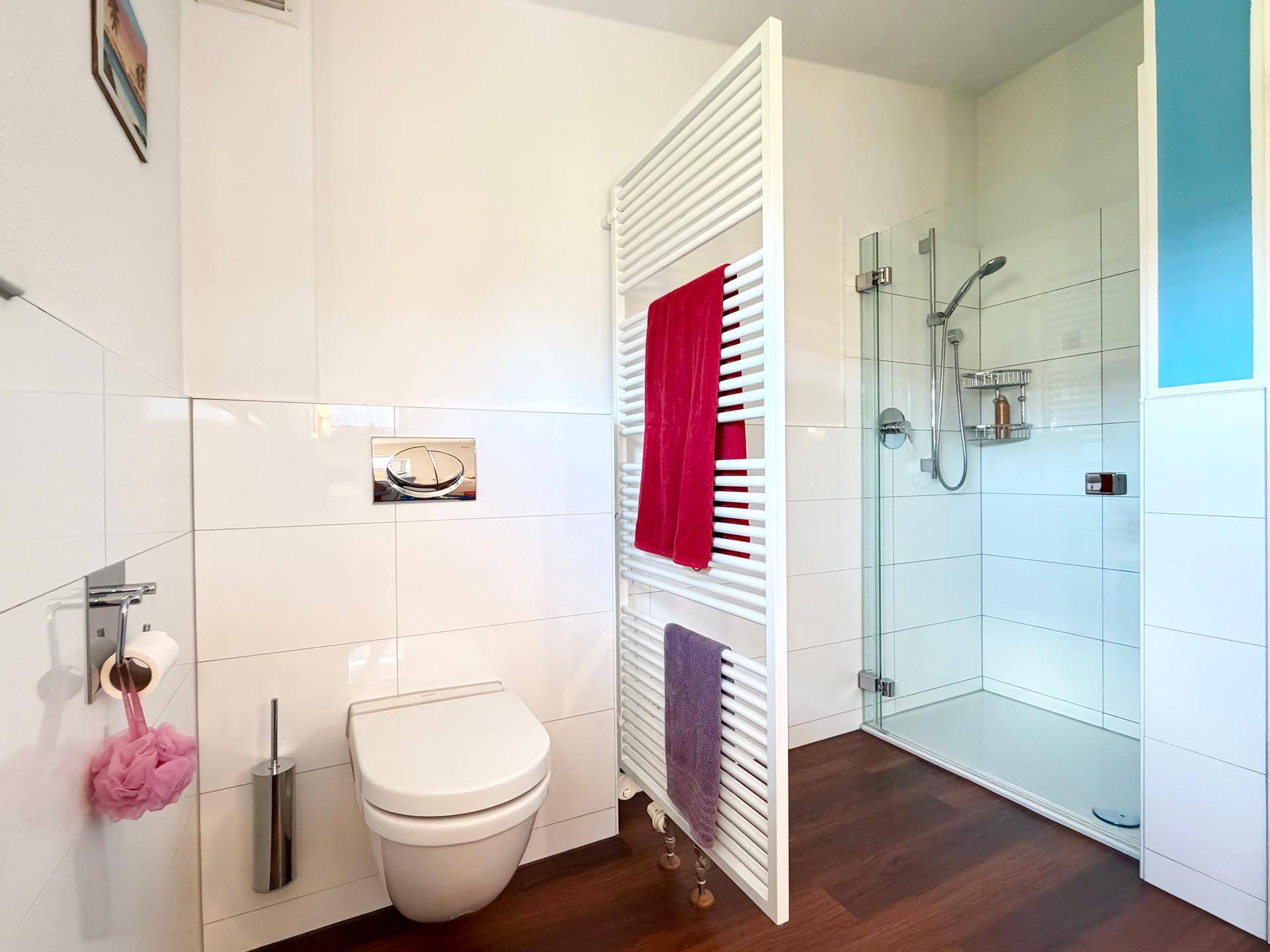 Helles Badezimmer mit Dusche, Toilette und beheiztem Handtuchhalter für Komfort.