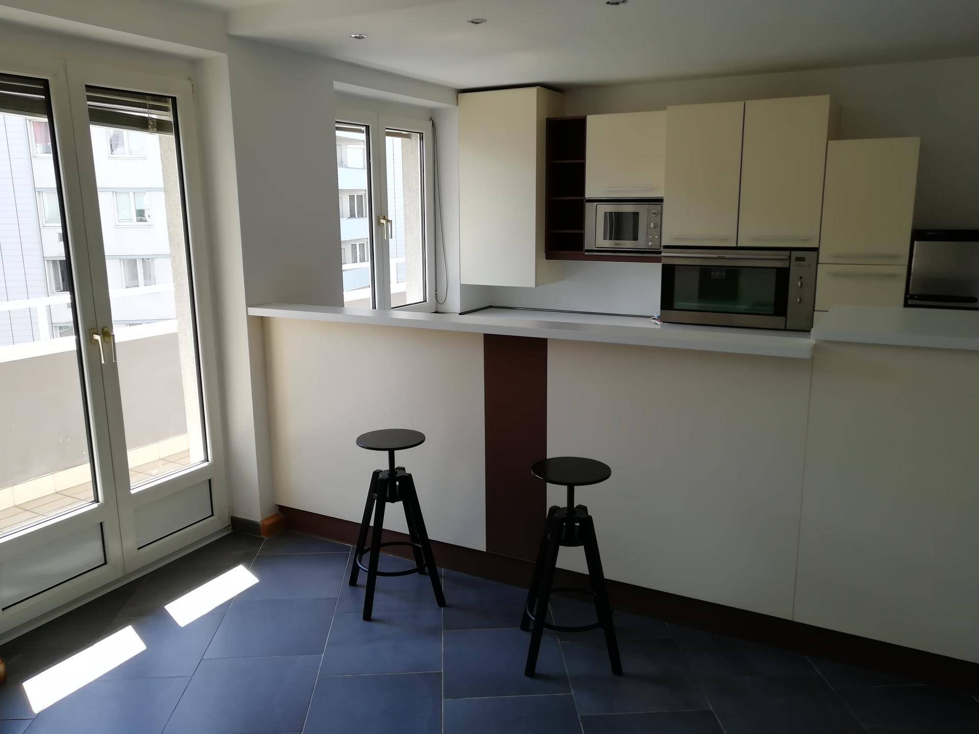Moderne Küche mit Frühstücksbar, integrierten Geräten und Zugang zu einem Balkon.