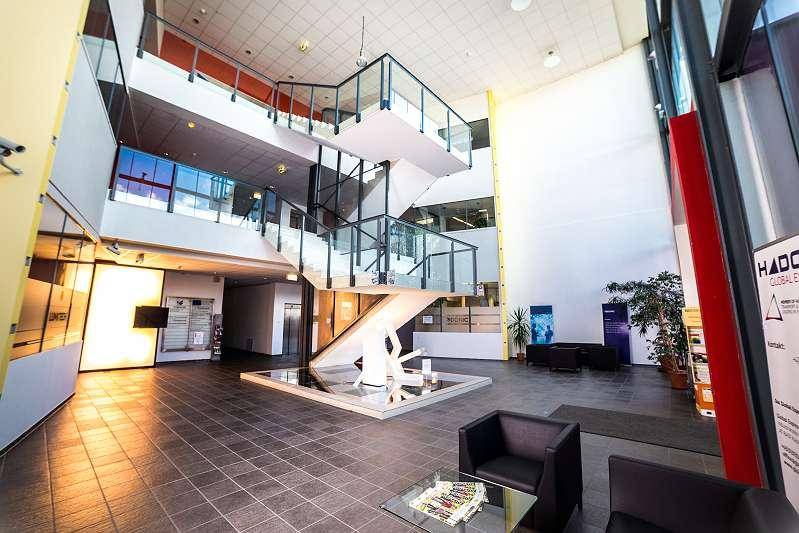 Geräumige und moderne Lobby mit beeindruckender Treppe, Glasgeländern und viel Tageslicht.