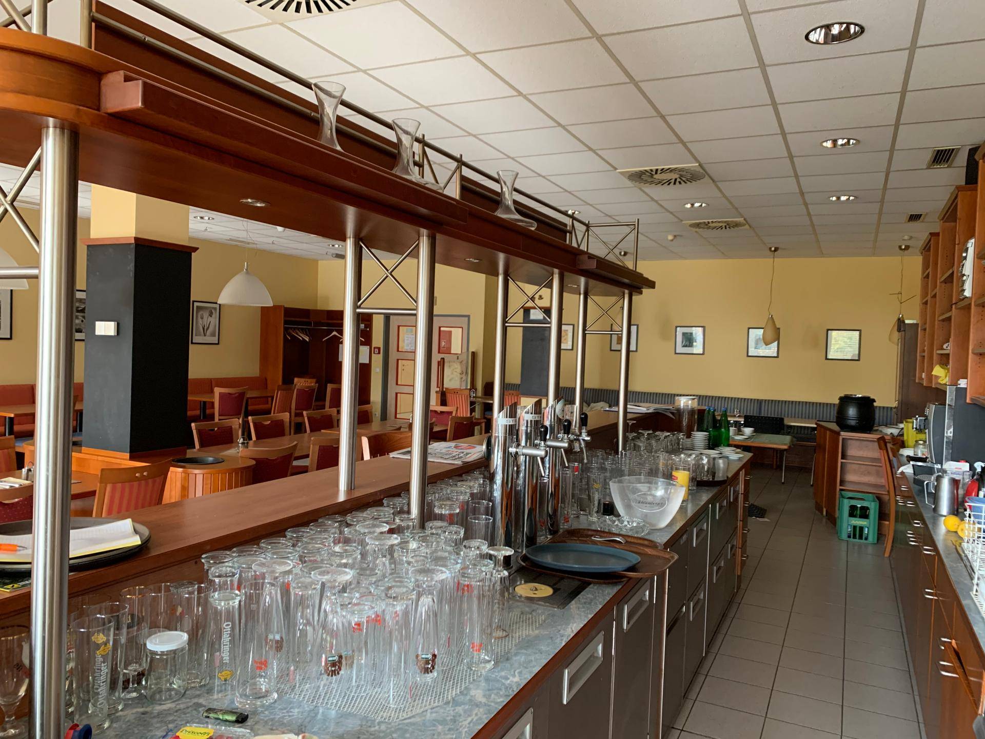 Gut ausgestatteter Barbereich im Speisesaal mit zahlreichen Gläsern, Zapfanlagen und Holztheke.