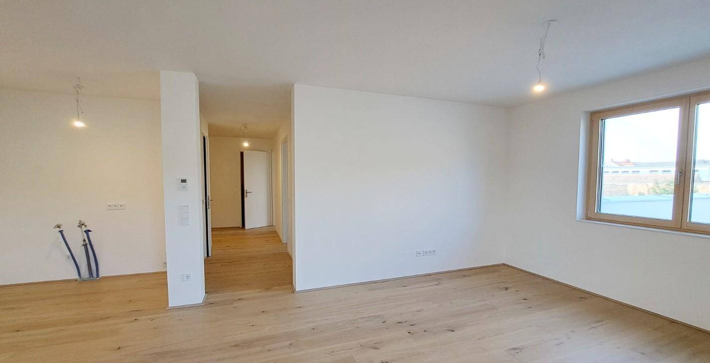 Geräumiger, unmöblierter Raum mit Holzboden und einem Fenster, das viel Tageslicht hereinlässt.