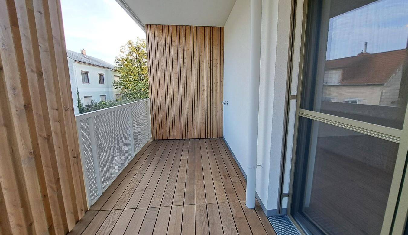 Geräumiger Balkon mit Holzboden und modernen Sichtschutzelementen, bietet Platz im Freien.