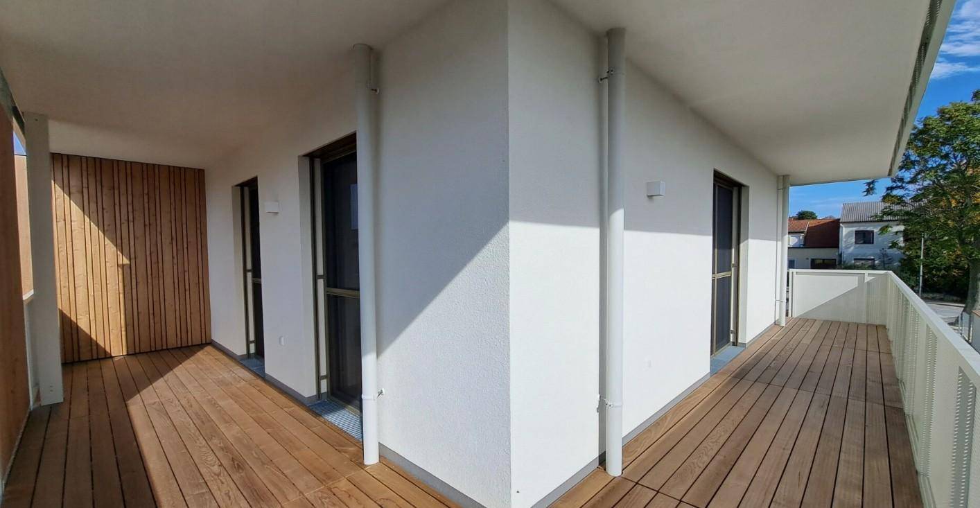 Geräumiger Balkon mit Holzboden und weißem Geländer, bietet einen angenehmen Außenbereich.