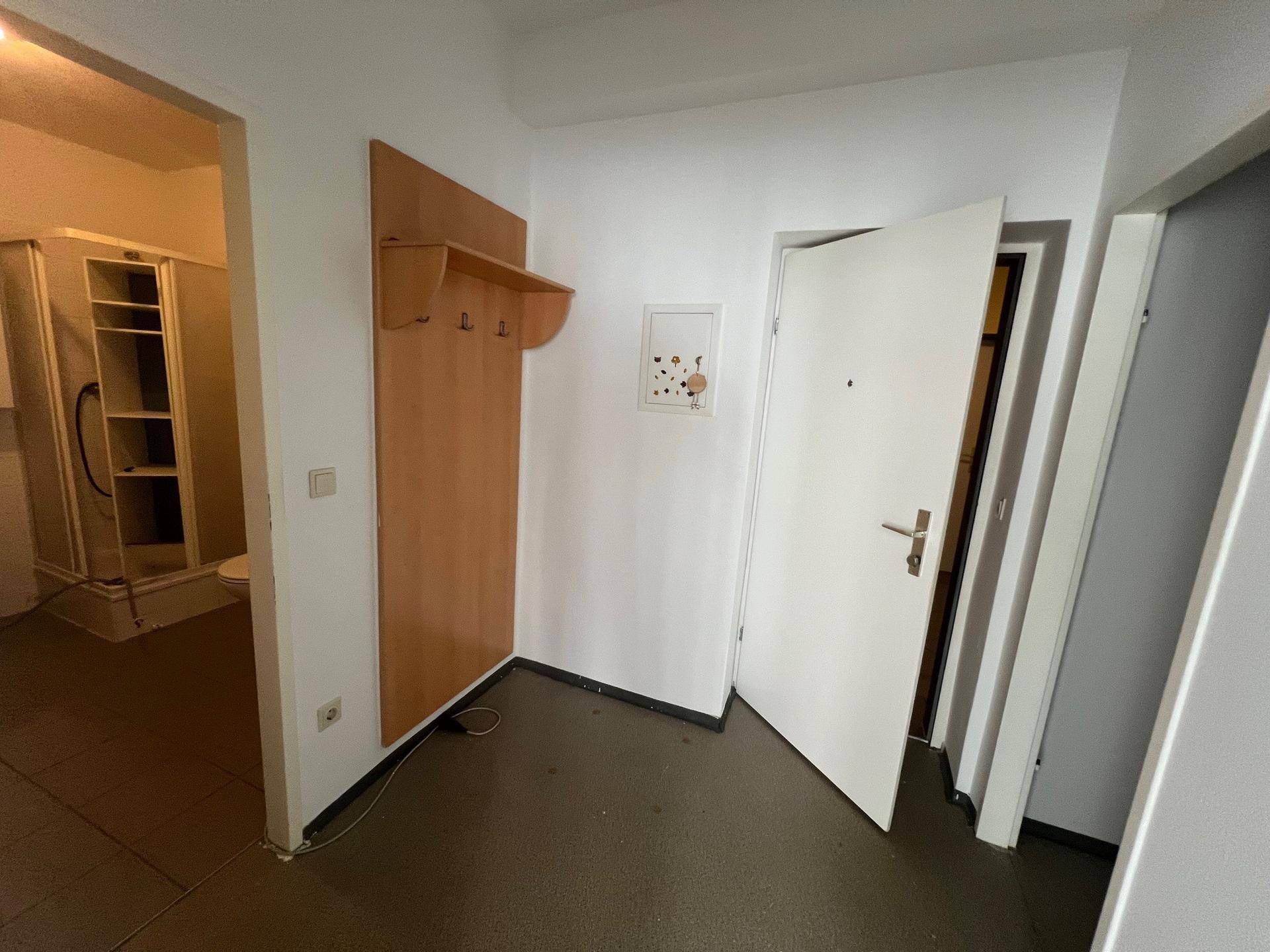 Eingangsbereich mit Garderobe und direktem Zugang zu einem Badezimmer mit Duschkabine.
