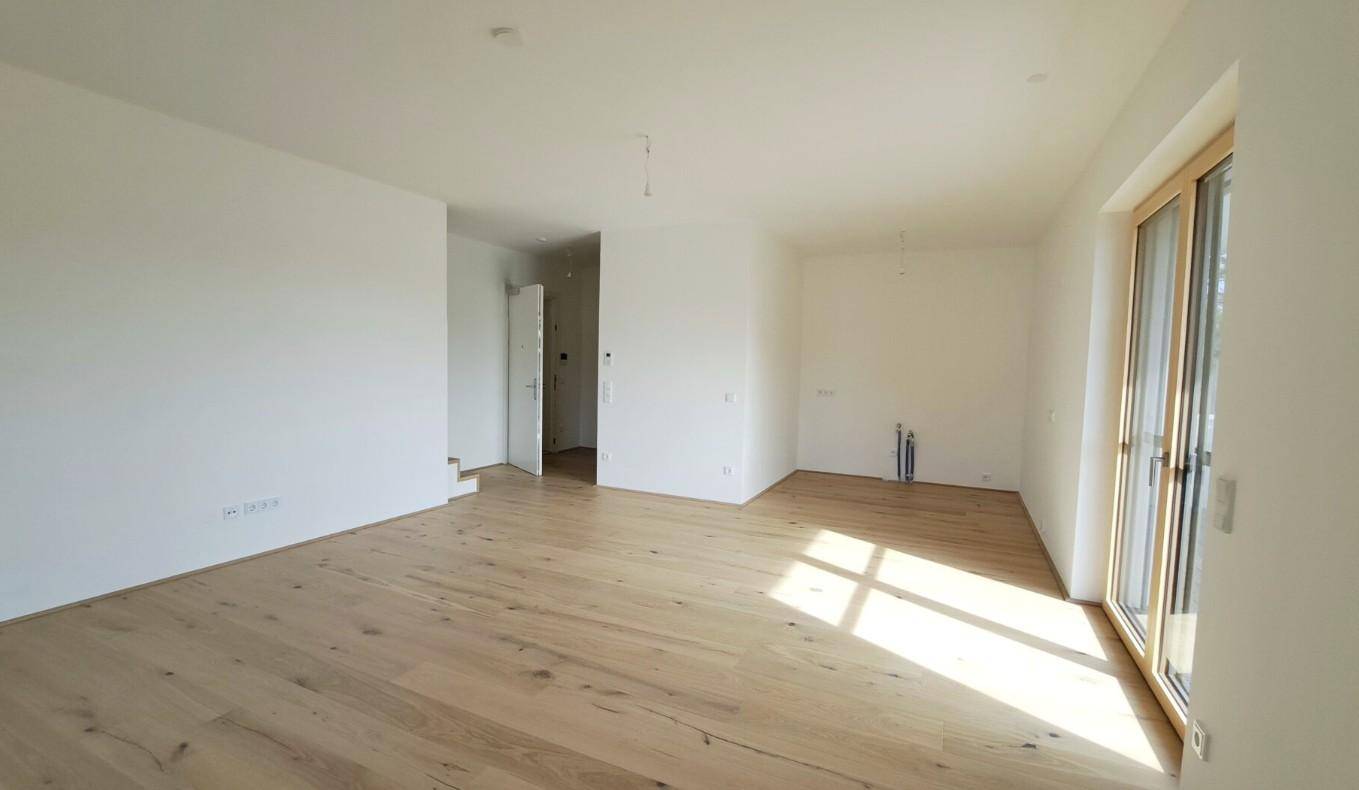 Lichtdurchfluteter Raum mit Holzboden und Zugang zum Balkon, bietet vielseitige Nutzungsmöglichkeiten.