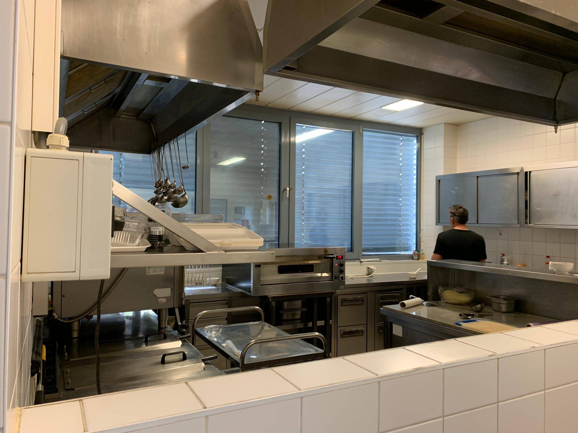 Professionelle Küche mit großen Dunstabzugshauben, Öfen und Arbeitsflächen aus Edelstahl, ideal für Gastronomie.