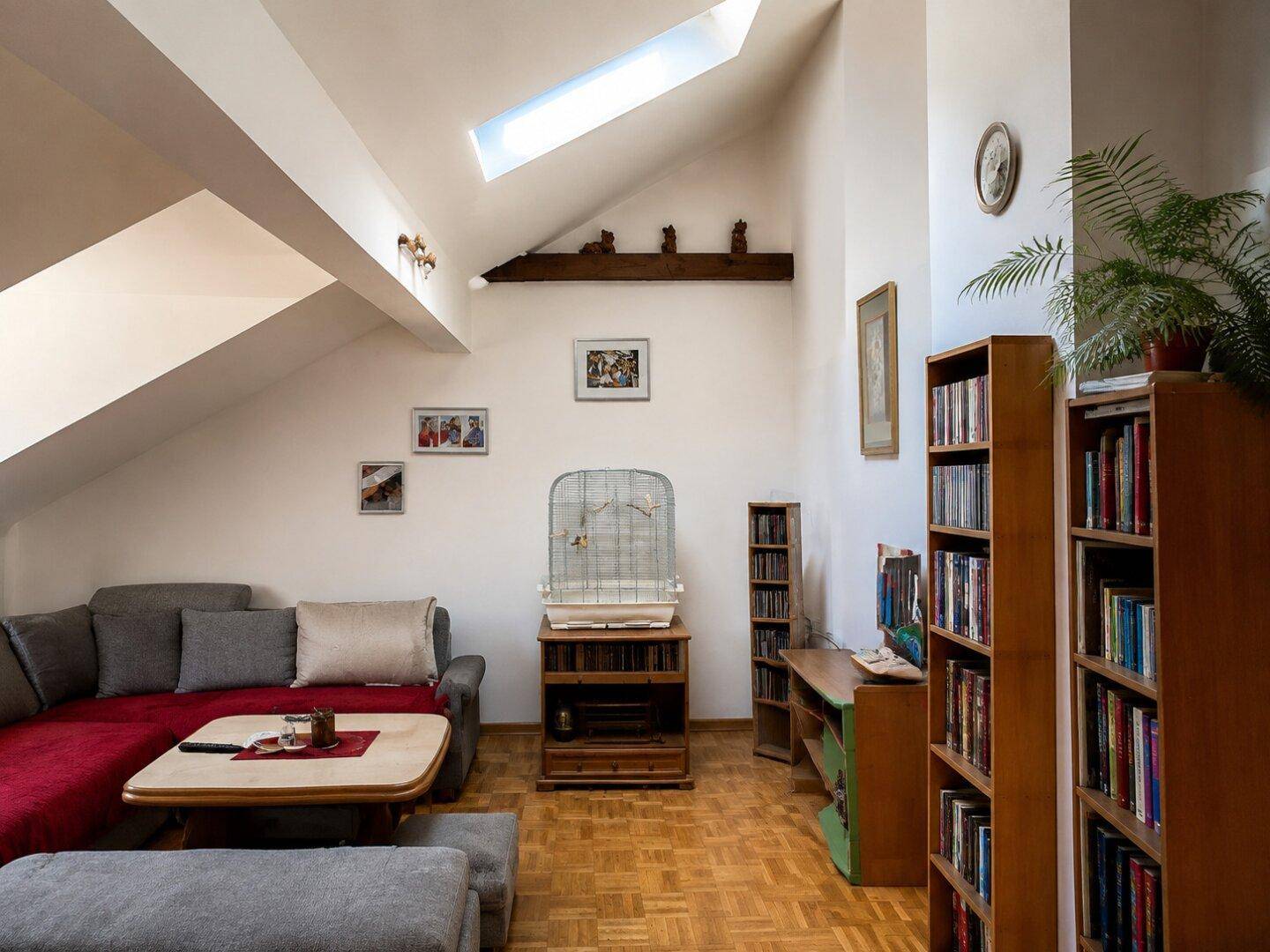 Helles Wohnzimmer mit Dachschrägen, Oberlicht und Bücherregalen, das viel Stauraum bietet.