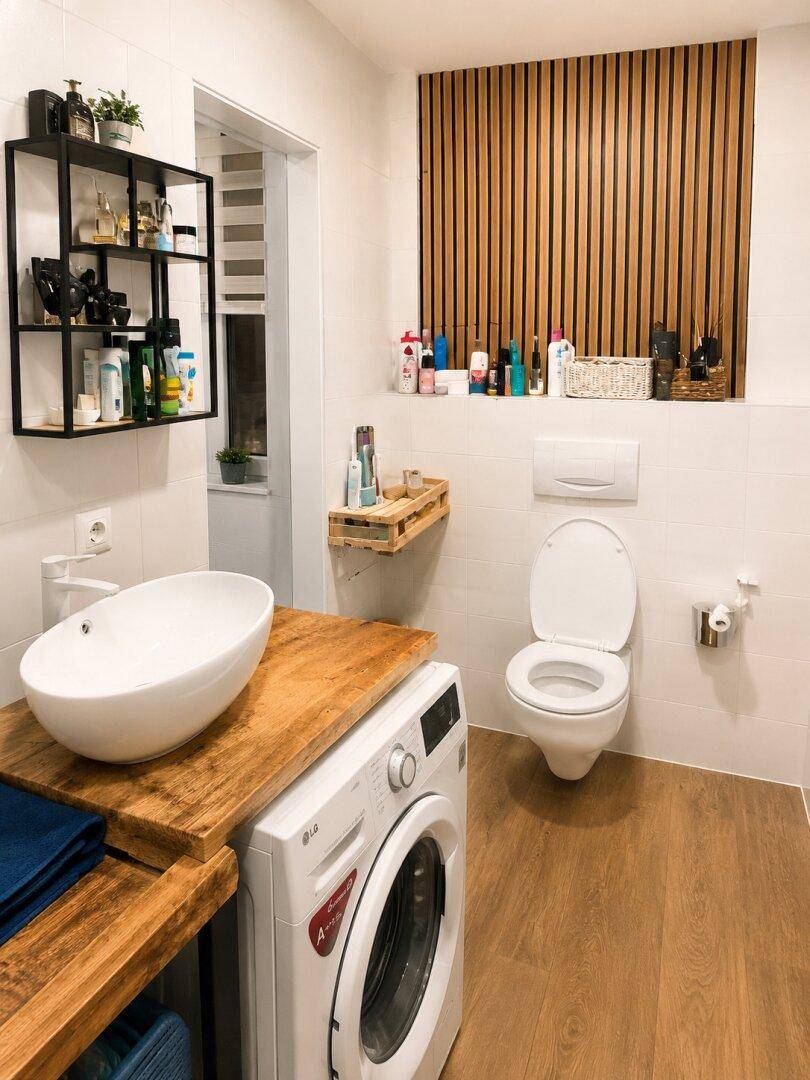 Modernes Badezimmer mit Holzakzenten, Waschbecken und wandmontierter Toilette.
