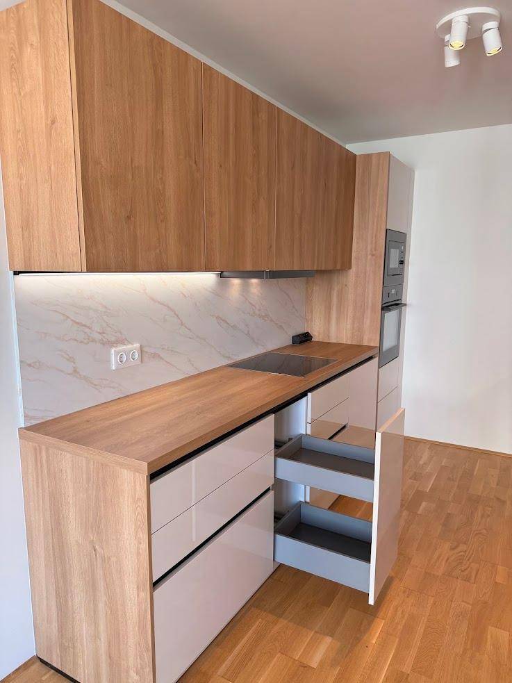 Funktionale Einbauküche mit Holz- und hellen Fronten, inklusive praktischem Auszugsschrank.
