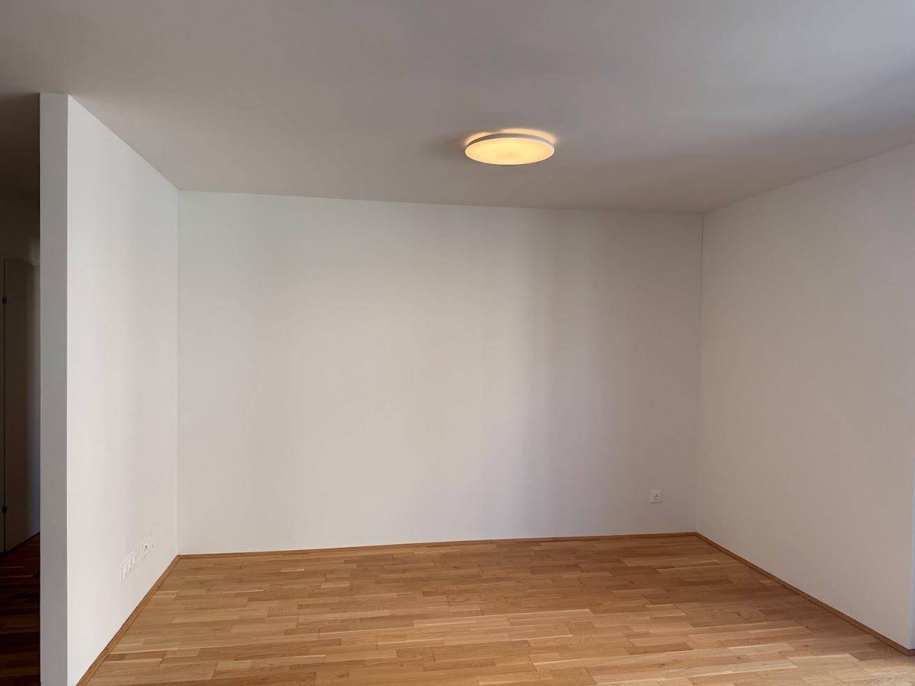 Leerer, heller Raum mit Holzboden und weiß gestrichenen Wänden, bereit zur Einrichtung.
