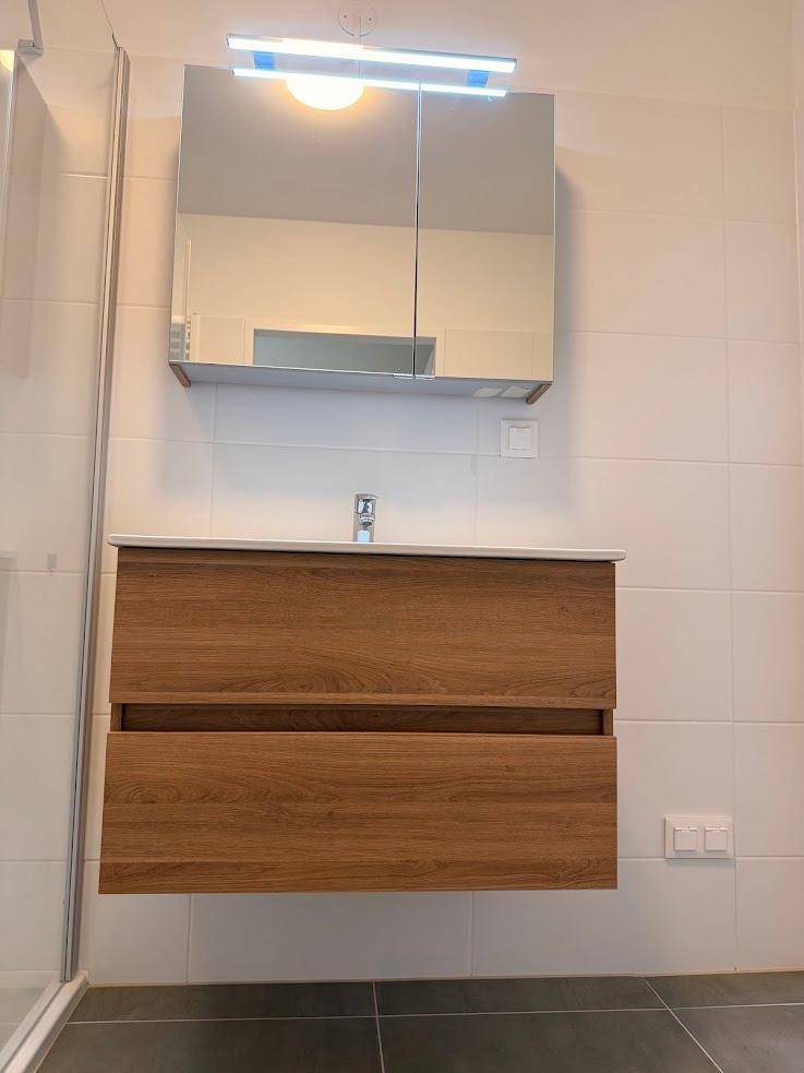 Moderner Waschtisch mit Holzunterschrank und Spiegelschrank im Badezimmer.