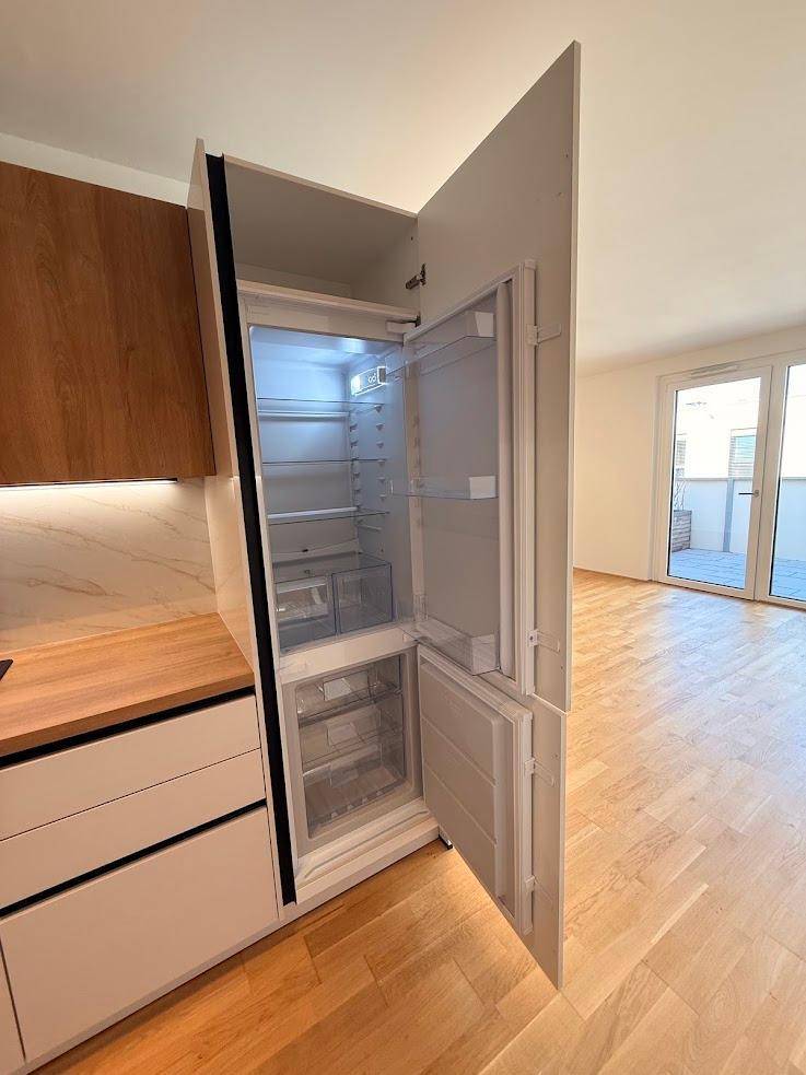 Moderne Einbauküche mit integriertem Kühlschrank und Holz-Arbeitsplatte.