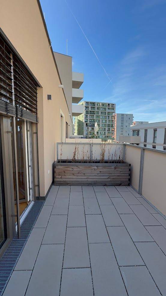 Geräumiger Balkon mit Fliesenboden und einem Holzkübel, bietet einen weiten Blick.