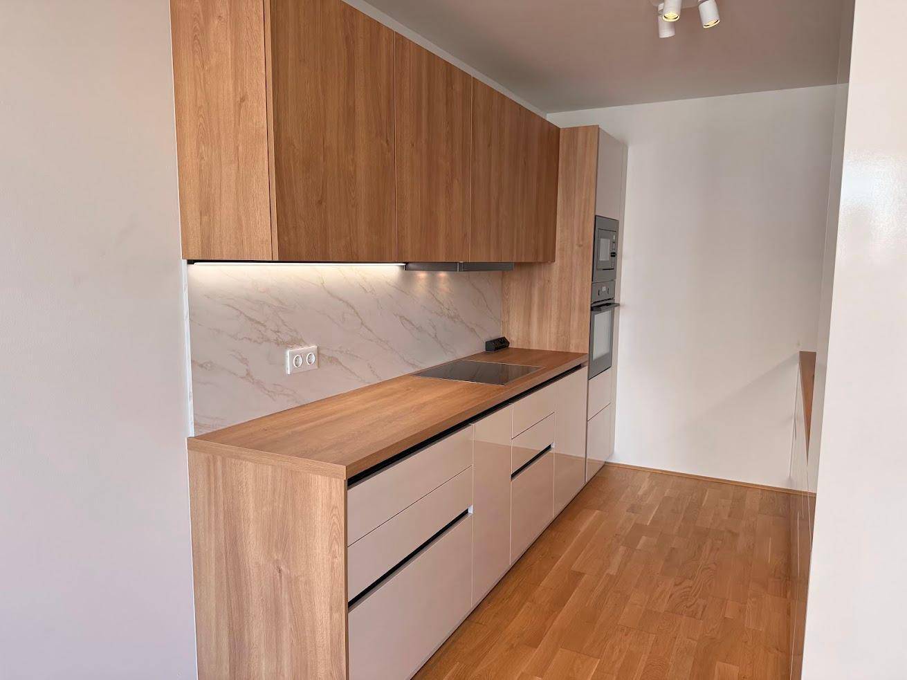 Geräumige, moderne Einbauküche mit Holz- und hellen Fronten sowie hochwertigen Geräten.