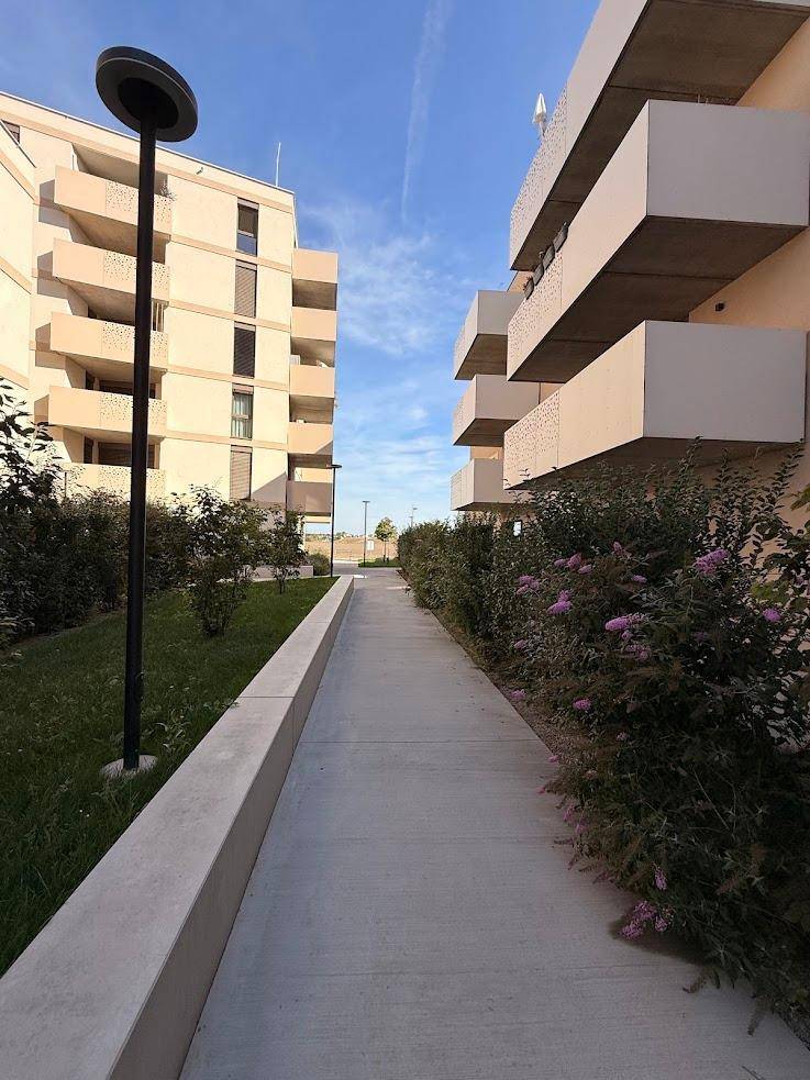 Außenansicht eines Wohnkomplexes mit Gehwegen, Grünflächen und modernen Gebäuden.