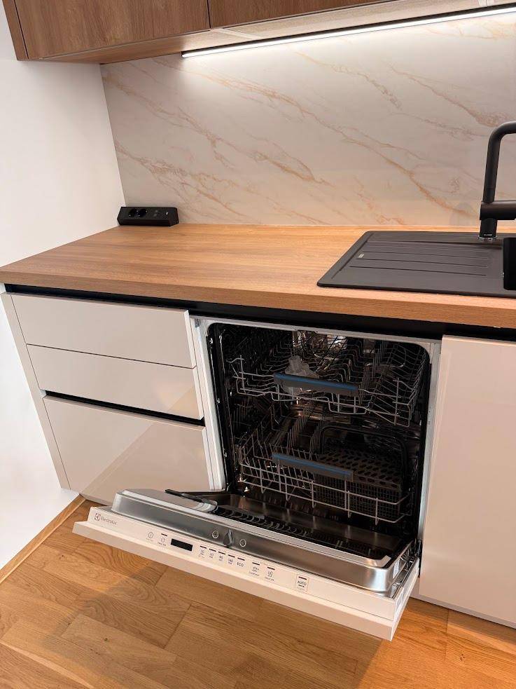 Moderne Küche mit integriertem Geschirrspüler und Holz-Arbeitsplatte.