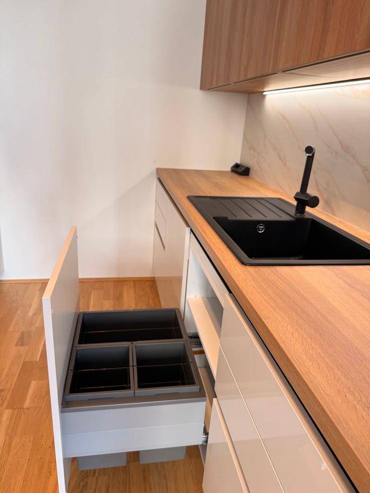 Moderne Küche mit schwarzer Spüle und integriertem Mülltrennsystem unter der Arbeitsplatte.