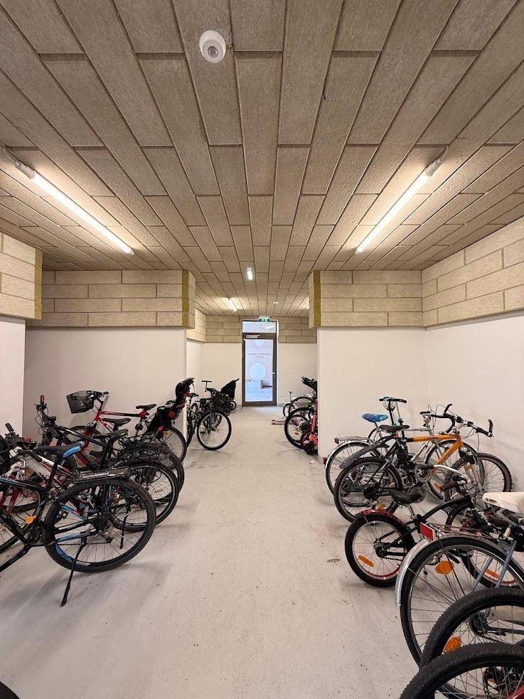 Geräumiger Fahrradraum im Untergeschoss mit vielen Fahrrädern und funktionaler Beleuchtung.