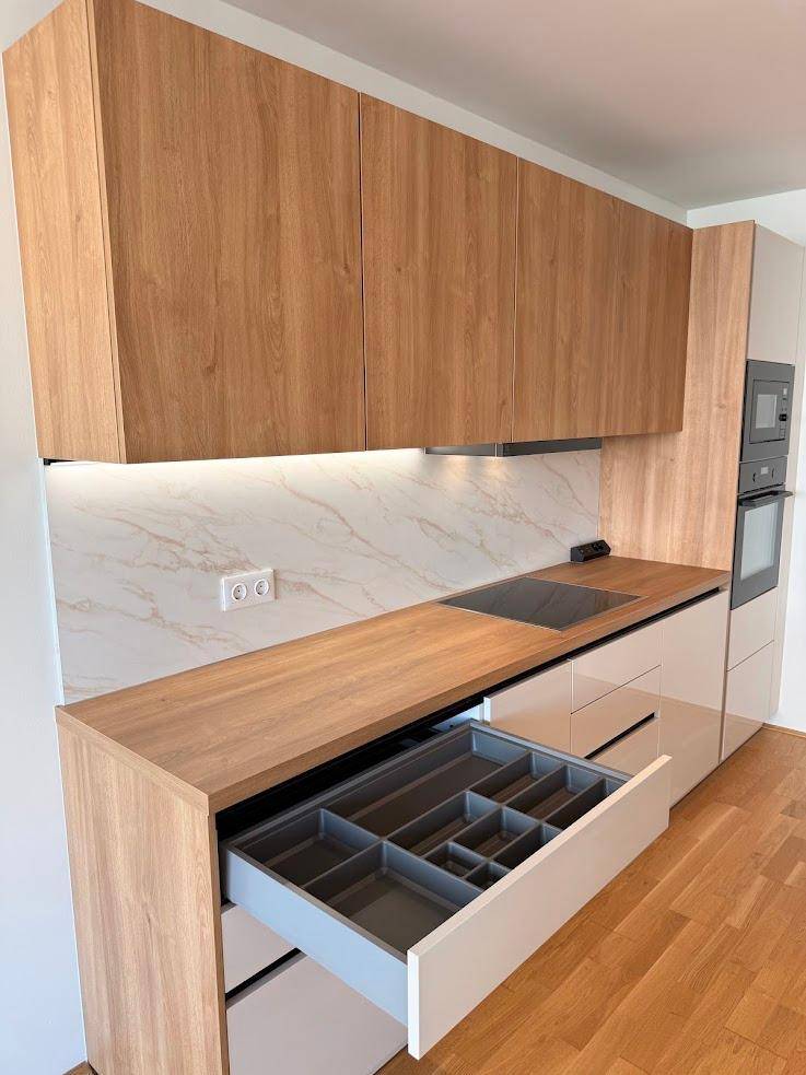Moderne Einbauküche mit Holzfronten, integrierten Geräten und praktischem Besteckkasten.