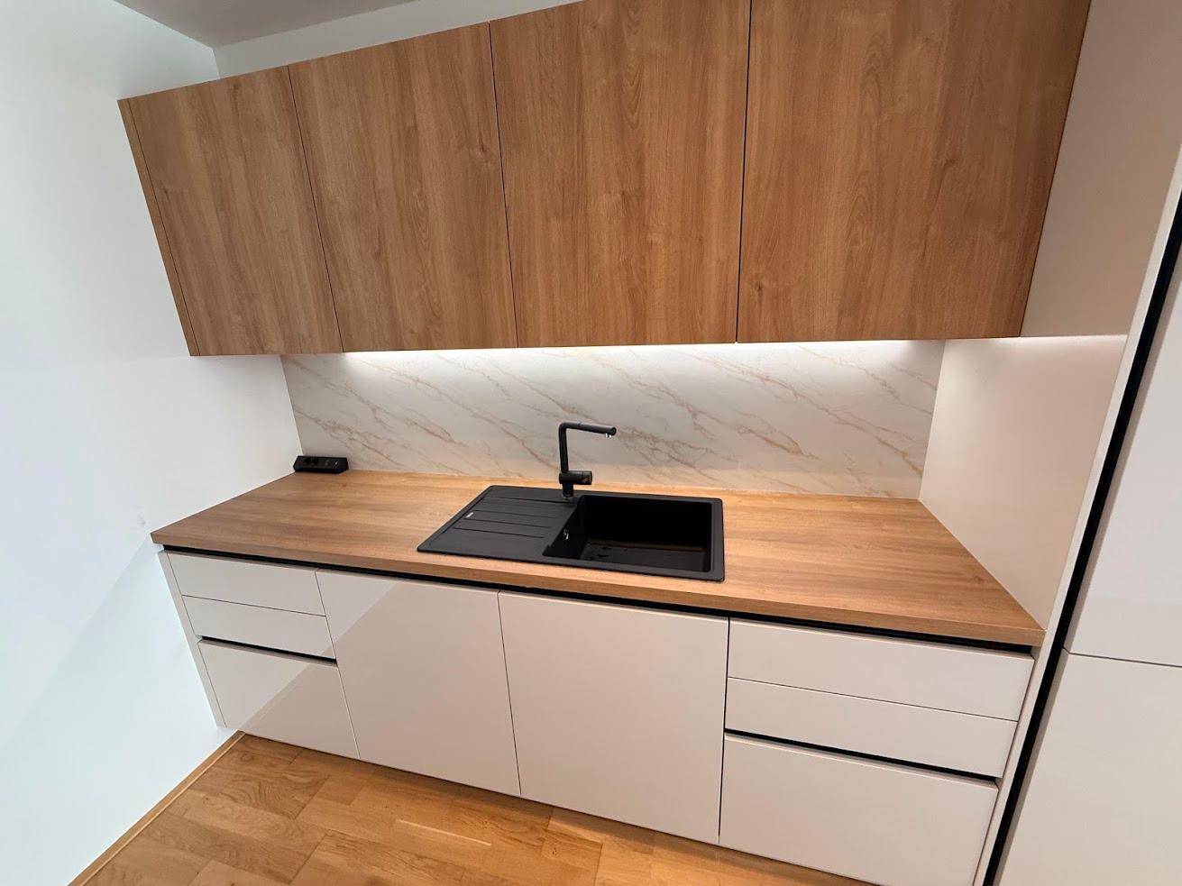 Helle, moderne Küche mit Holz-Arbeitsplatte, schwarzer Spüle und integrierten Unterschränken.